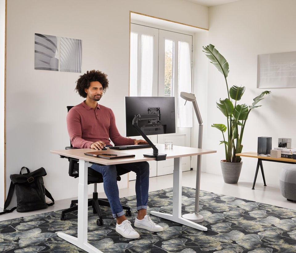 Landscapexl Ahrend Home Hvm Desk In White With Oak Tabletop And Black Ease Office Chair With Grey Recharge And Pyramid Bench With Male Model Thinking In A Work From Home Set